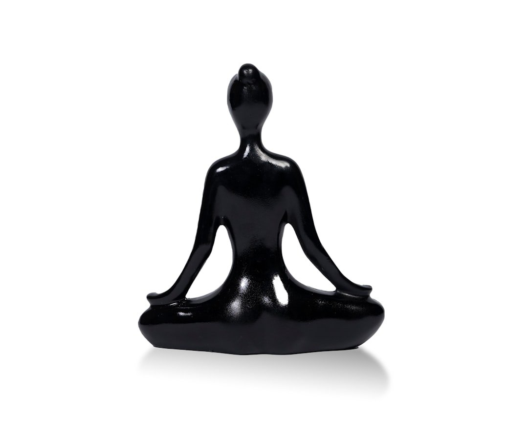 a black statue of a person sitting in a yoga position